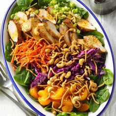 a salad with chicken, carrots, and cashews on a white plate