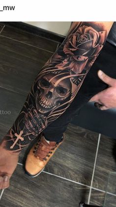 a man's arm with a skull and cross tattoo on the left side of his leg