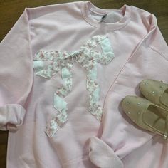 a pair of shoes sitting next to a pink shirt with bows on the front and bottom