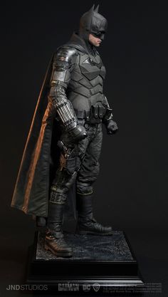 the dark knight batman statue is posed on a black surface with his hands in his pockets