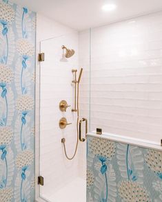 a shower with blue and white wallpaper in a bathroom