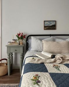 a bed sitting next to a table with a basket and flowers on top of it