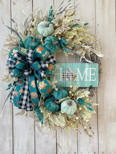 a wreath that has been decorated with blue and green flowers, leaves and a welcome home sign on it