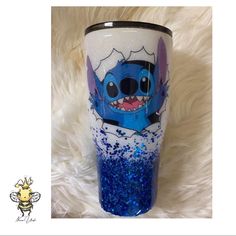 a blue and white tumbler cup with stitching on the side sitting on a fur surface