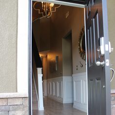 an open door leading to a hallway with chandelier