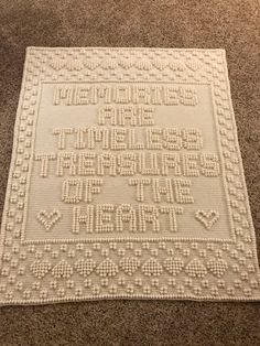 a white crocheted rug on the floor with words written in small letters and dots