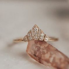 a diamond ring sitting on top of a piece of pink quartz with white diamonds around it