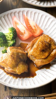 a white plate topped with meat and veggies on top of a wooden table