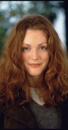 a woman with long red hair smiling at the camera