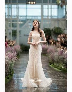 a woman in a wedding dress walking down a runway