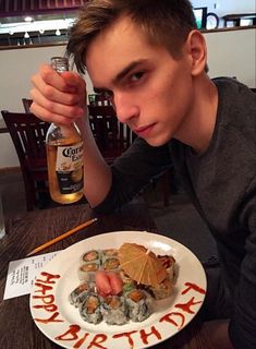 a young man sitting at a table with a plate of food