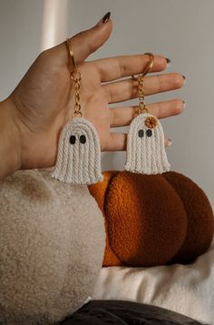 a hand holding two knitted ghost key chains