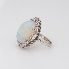 Stylish vintage natural opal ring (circa 1970s to 1980s) crafted in 14 karat white gold.   Natural opal measures 22mm x 14.5mm (estimated at 22 carats). The opal is in very good condition and free of cracks or crisps. Round brilliant cut diamonds total an estimated 1.40 carats (estimated at H-I colour and VS2-SI1 clarity).   The opal is full of colour and fire (opals are difficult to photograph and the true colours of the opal does not show in the pictures). The colour matrix is vivid from merma Formal Opal Rings With Polished Finish, Opal Rings With Polished Finish For Formal Occasions, Formal Opal Ring With Polished Finish, Formal White Ethiopian Opal Ring, White Ethiopian Opal Ring For Formal Occasions, Formal Oval Cabochon Opal Ring, Formal Oval Cabochon Opal Ring Fine Jewelry, Oval Opal Ring With Polished Finish, Elegant Ethiopian Opal Ring Oval Cabochon