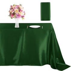 a green table cloth with flowers in a vase and plates on the table next to it