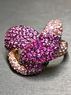 A dazzling cocktail ring done in 14K rose gold by EFFY. It has been pavè set with approximately 8cttw in various toned natural pink sapphires and bold knot or twist design. Dimensions/Weight: Ring measures 1" top to bottom and weighs 12.6g. Size 12 (sizable). Condition: All stones are secure and in perfectly wearable condition. Makers marks and purity stamps are present and legible. R-OPP Luxury Pink Multi-stone Ruby Ring, Formal Pink Multi-stone Sapphire Ring, Pink Diamond Cluster Ruby Ring, Luxury Pink Rings With Pave Setting, Pink Cluster Ruby Ring With Diamond, Dazzling Pink Ruby Gemstone Ring, Luxury Pink Ruby Ring For Anniversary, Pink Multi-stone Sapphire Ring In Fine Jewelry Style, Pink Multi-stone Sapphire Ring, Fine Jewelry