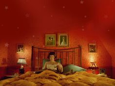 a woman laying in bed with red walls and pictures on the wall above her head