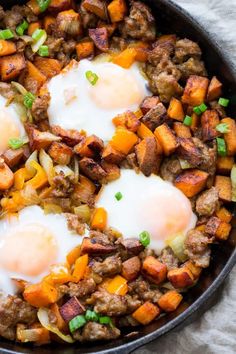 two eggs are being cooked in a skillet with sausage and sweet potato hash browns