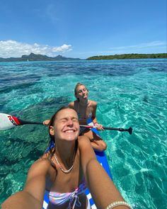 two women are in the water with their paddles out and one woman is smiling