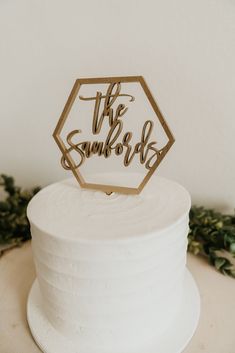 a white cake topped with a wooden sign that says the sunbirds on it