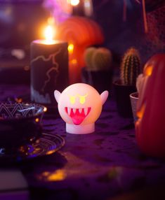 a table topped with candles and a small toy monster face on it's head