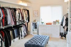 a closet with clothes on racks and a footstool