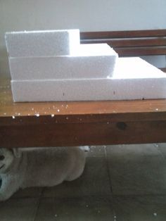 a dog laying on the floor under a table with some blocks of foam sitting on top of it