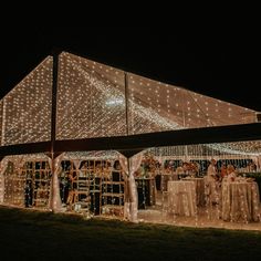 a large tent with lights on it and people sitting at tables under the canopy in front of it