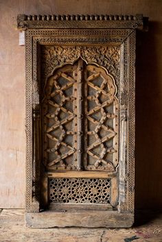 an old wooden door with intricate carvings on the front and back sides, in a room