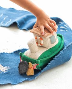 a child's hand reaching for a toy house on top of a blue towel