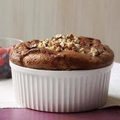 a muffin in a white dish next to some berries