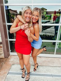 two beautiful young women standing next to each other in front of a window with their arms around each other