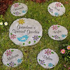 four personalized stepping stones in the grass with daisies and flowers around them on top