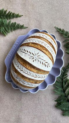 a blue platter filled with sliced bread next to green leaves on a gray surface