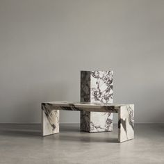 three marble tables stacked on top of each other in an empty room with grey walls