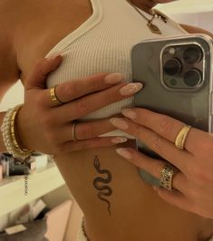 a woman is holding her cell phone up to her stomach and showing off her tattoos