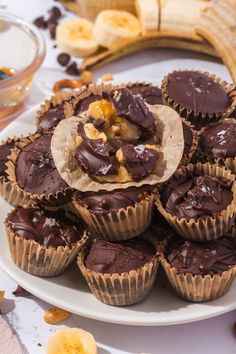 chocolate cupcakes on a plate with bananas and other food items in the background