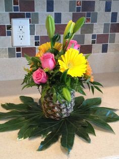 a pineapple vase filled with flowers on top of a kitchen counter next to a light switch