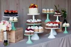 a table topped with lots of cakes and cupcakes on top of wooden trays