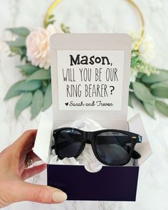 a person holding up a box with sunglasses in it and the words mason will you be our ring bearer?