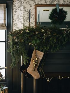 christmas stockings hanging from the mantle in front of a fireplace with greenery and candles