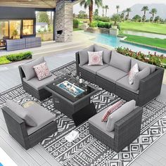 an outdoor living room with grey couches and coffee table in front of a pool