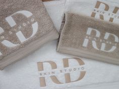 three towels with the words skin studio printed on them, and two are folded in front of each other