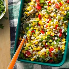 a green dish filled with corn and vegetables next to a bowl of cilantro