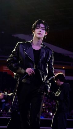 a male model in a black leather jacket and pants on the runway at a fashion show