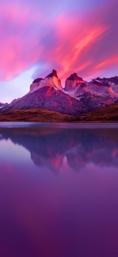 the mountain range is reflected in the still water at sunset with pink and purple clouds