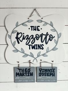 two signs hanging on the side of a white wooden wall that says the rissotto twins