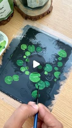 someone is painting water lilies on a piece of wood with green paint and a blue brush