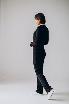 a woman in black is standing with her hands on her hips and looking off to the side