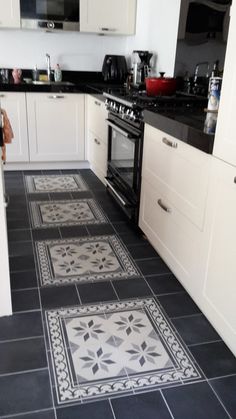 a kitchen with black and white tile flooring next to a stove top oven in the corner