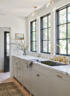 a kitchen with marble counter tops and gold faucets in the window sill